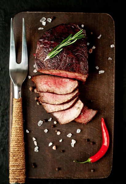 Siyah taş arka plan üzerinde baharat ve biberiye dal ile Taze ızgara biftek