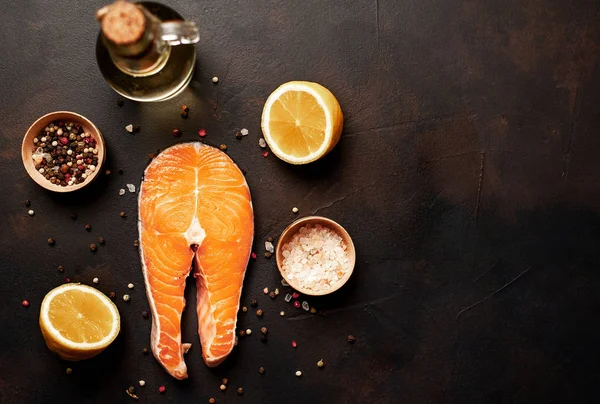 Siyah taş arka plan üzerinde baharat ve limon ile taze çiğ somon biftek