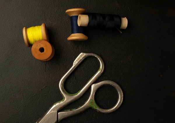 siyah arka plan üzerinde dikiş makaraları yığını ile terzi makasları 