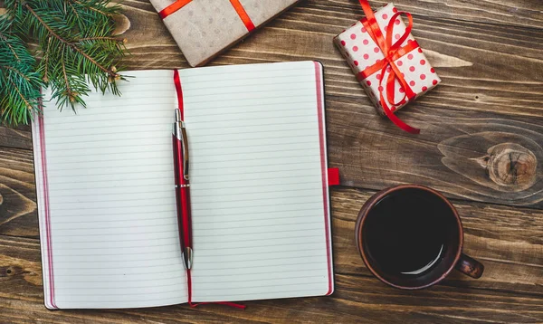 Eski ahşap arka plan üzerinde kırmızı yay ve boş defter ile hediye kutuları yığını 