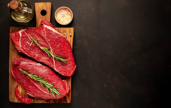 Taş arka planda baharat ve biberiye ile çiğ sığır biftek
