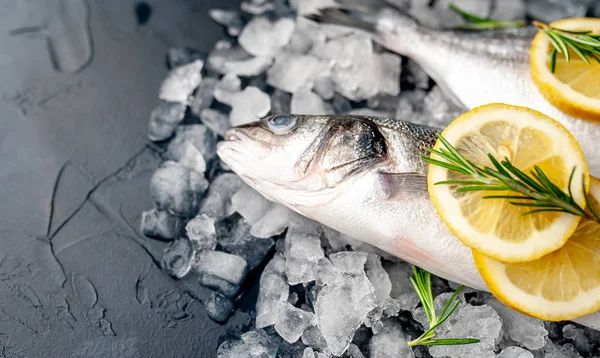 Soğuk ezilmiş buz yığını üzerinde limon dilimleri ve biberiye ile taze balık yakın görünümü