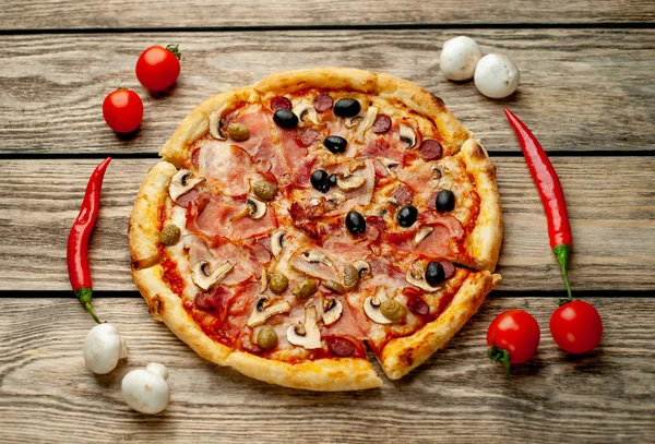 Ahşap arka plan üzerinde mantar, domates, zeytin ve jambon ile taze ev yapımı pizza