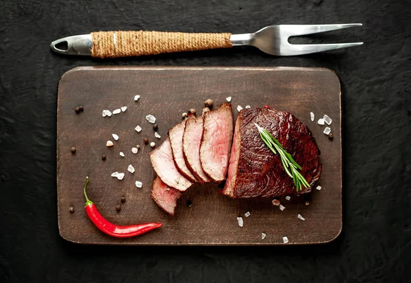 Siyah taş arka plan üzerinde baharat ve biberiye dal ile Taze ızgara biftek