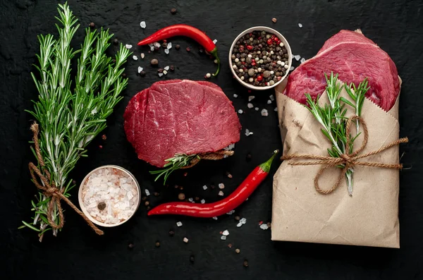 Çiğ taze biftek siyah taş arka plan üzerinde baharat ile kağıt sarılmış 