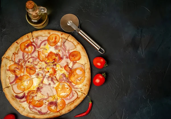 Fresh vegetable pizza with ham on black stone background