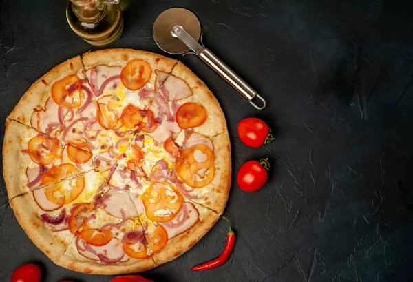 Fresh vegetable pizza with ham on black stone background