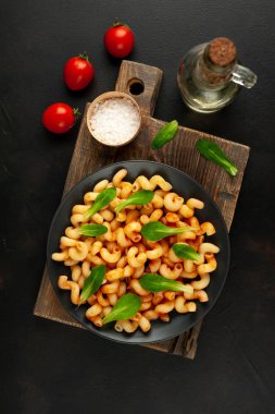 taş siyah arka plan üzerinde ahşap doğrama tahtası üzerinde domates soslu makarna