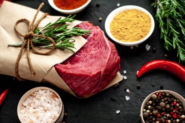 Siyah taş arka plan üzerinde baharat ile Çiğ taze biftek