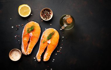 Siyah taş arka plan üzerinde baharat ve limon ile taze çiğ somon biftek