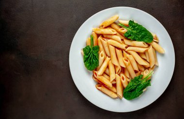 taş siyah arka plan üzerinde yeşil yaprakları ile servis domates soslu makarna