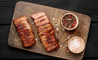 siyah ahşap arka plan üzerinde ahşap doğrama tahtası üzerinde baharat ile ızgara domuz biftek 