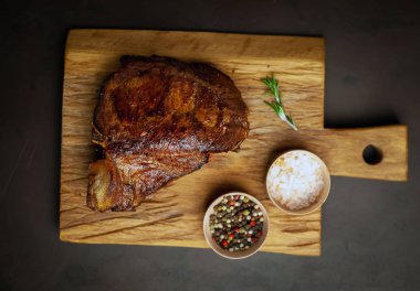 Siyah taş arka plan üzerinde ahşap doğrama tahtası üzerinde baharat ile Yağlı ızgara domuz biftek