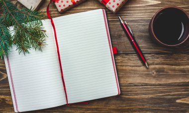 Eski ahşap arka plan üzerinde kırmızı yay ve boş defter ile hediye kutuları yığını 