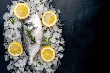 Soğuk ezilmiş buz yığını üzerinde limon dilimleri ve biberiye ile taze balık yakın görünümü