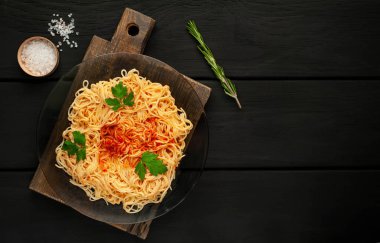 koyu taş arka plan üzerinde domates sosu ve maydanoz yaprakları ile İtalyan spagetti makarna