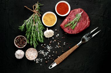 Siyah taş arka plan üzerinde baharat ile Çiğ taze biftek
