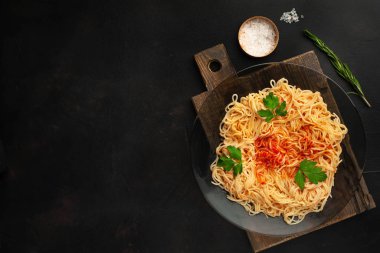 koyu taş arka plan üzerinde domates sosu ve maydanoz yaprakları ile İtalyan spagetti makarna