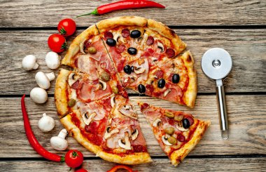 Ahşap arka plan üzerinde mantar, domates, zeytin ve jambon ile taze ev yapımı pizza