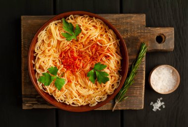 koyu taş arka plan üzerinde domates sosu ve maydanoz yaprakları ile İtalyan spagetti makarna