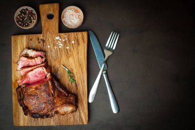 Siyah taş arka plan üzerinde ahşap doğrama tahtası üzerinde baharat ile Yağlı ızgara domuz biftek