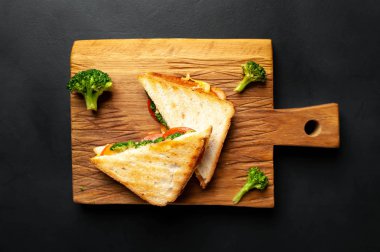 Ahşap doğrama tahtasında jambon, taze brokoli ve peynirile taze ızgara sandviçler