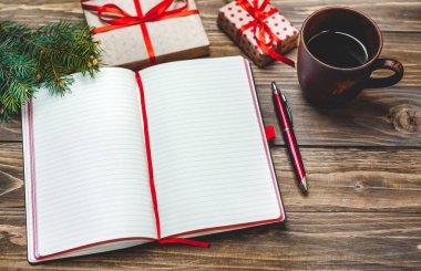 Eski ahşap arka plan üzerinde kırmızı yay ve boş defter ile hediye kutuları yığını 