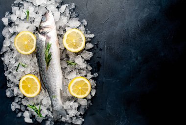 Soğuk ezilmiş buz yığını üzerinde limon dilimleri ve biberiye ile taze balık yakın görünümü