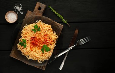 koyu taş arka plan üzerinde domates sosu ve maydanoz yaprakları ile İtalyan spagetti makarna