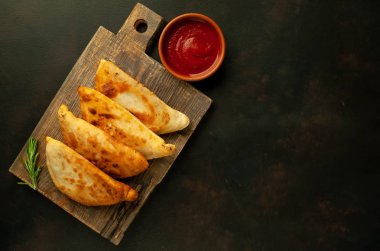 Ahşap doğrama tahtası üzerinde domates soslu Geleneksel Latin Amerika kızarmış empanadas 