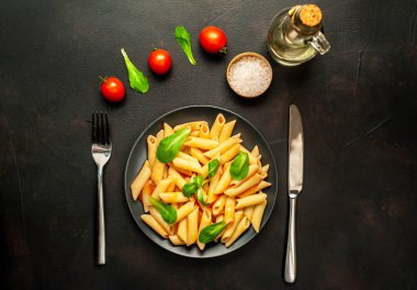 domates soslu makarna, yeşil yapraklar ve taş siyah arka plan üzerinde olgun domates