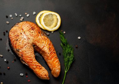 Siyah taş arka plan üzerinde baharat ve limon ile ızgara somon biftek