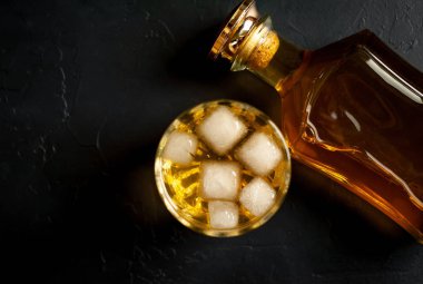 Siyah arka planda buz küpleri ve viski şişesi ile viski Bir bardak 