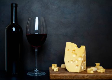 Ahşap tahta üzerinde Maasdam peynirsiyah taş arka plan üzerinde kırmızı şarap ile servis 