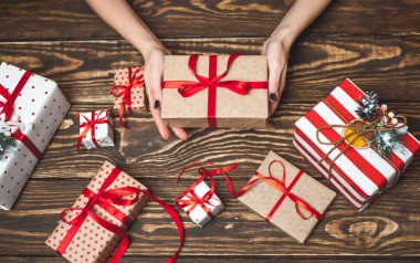 Eski ahşap arka plan üzerinde kırmızı yay ile kadın elleri dekorasyon hediye kutuları 