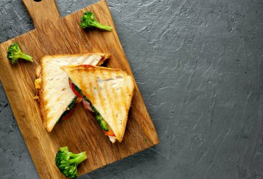 Ahşap doğrama tahtasında jambon, taze brokoli ve peynirile taze ızgara sandviçler