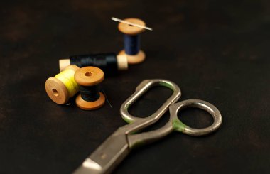 siyah arka plan üzerinde dikiş makaraları yığını ile terzi makasları 