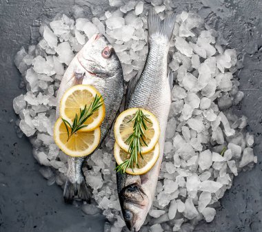 Soğuk ezilmiş buz yığını üzerinde limon dilimleri ve biberiye ile taze balık yakın görünümü
