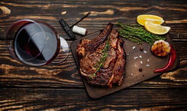 Taze kavrulmuş biftek ahşap doğrama tahtası üzerinde limon dilimleri ve ızgara sarımsak ile servis
