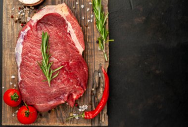 Ahşap doğrama tahtasında biberiye, domates ve biberiye ile taze çiğ biftek 