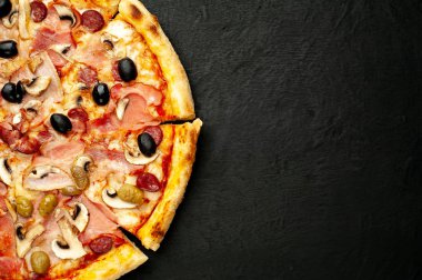 Siyah taş arka plan üzerinde mantar, domates, zeytin ve jambon ile taze ev yapımı pizza