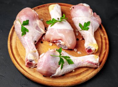 Baharat, tuz ve maydanoz siyah taş arka plan üzerinde yuvarlak ahşap tahta üzerinde yaprakları ile Tavuk bacakları