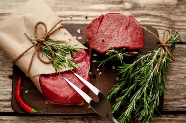 Ahşap arka plan üzerinde zanaat kağıt sarılmış baharat ile Çiğ biftek 