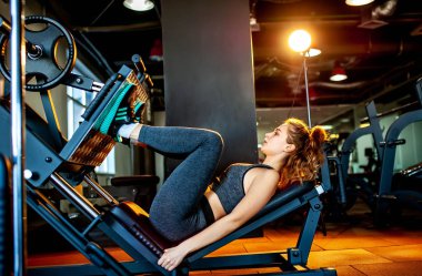 Genç sporcu kadın boş spor salonunda kas çalıştırıyor.  