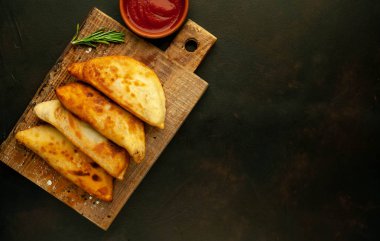 Ahşap doğrama tahtası üzerinde domates soslu Geleneksel Latin Amerika kızarmış empanadas 