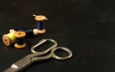 siyah arka plan üzerinde dikiş makaraları yığını ile terzi makasları 