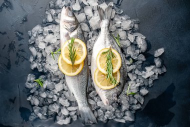 Soğuk ezilmiş buz yığını üzerinde limon dilimleri ve biberiye ile taze balık yakın görünümü