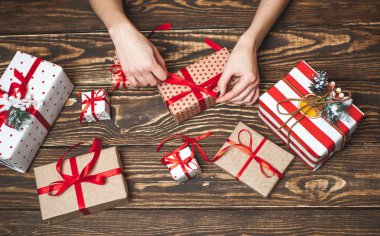 Eski ahşap arka plan üzerinde kırmızı yay ile kadın elleri dekorasyon hediye kutuları 