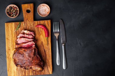 Siyah taş arka plan üzerinde doğrama tahtası üzerinde baharat ve biber ile Yağlı ızgara domuz biftek