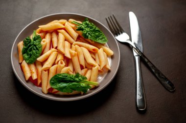 taş siyah arka plan üzerinde yeşil yaprakları ile servis domates soslu makarna